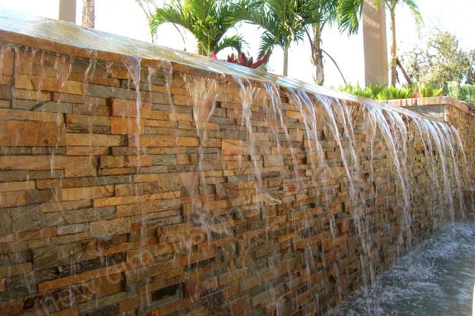 Spillway for an infinity edge pool featuring a stacked stone wall laid over a waterproofing membrane for long term durability